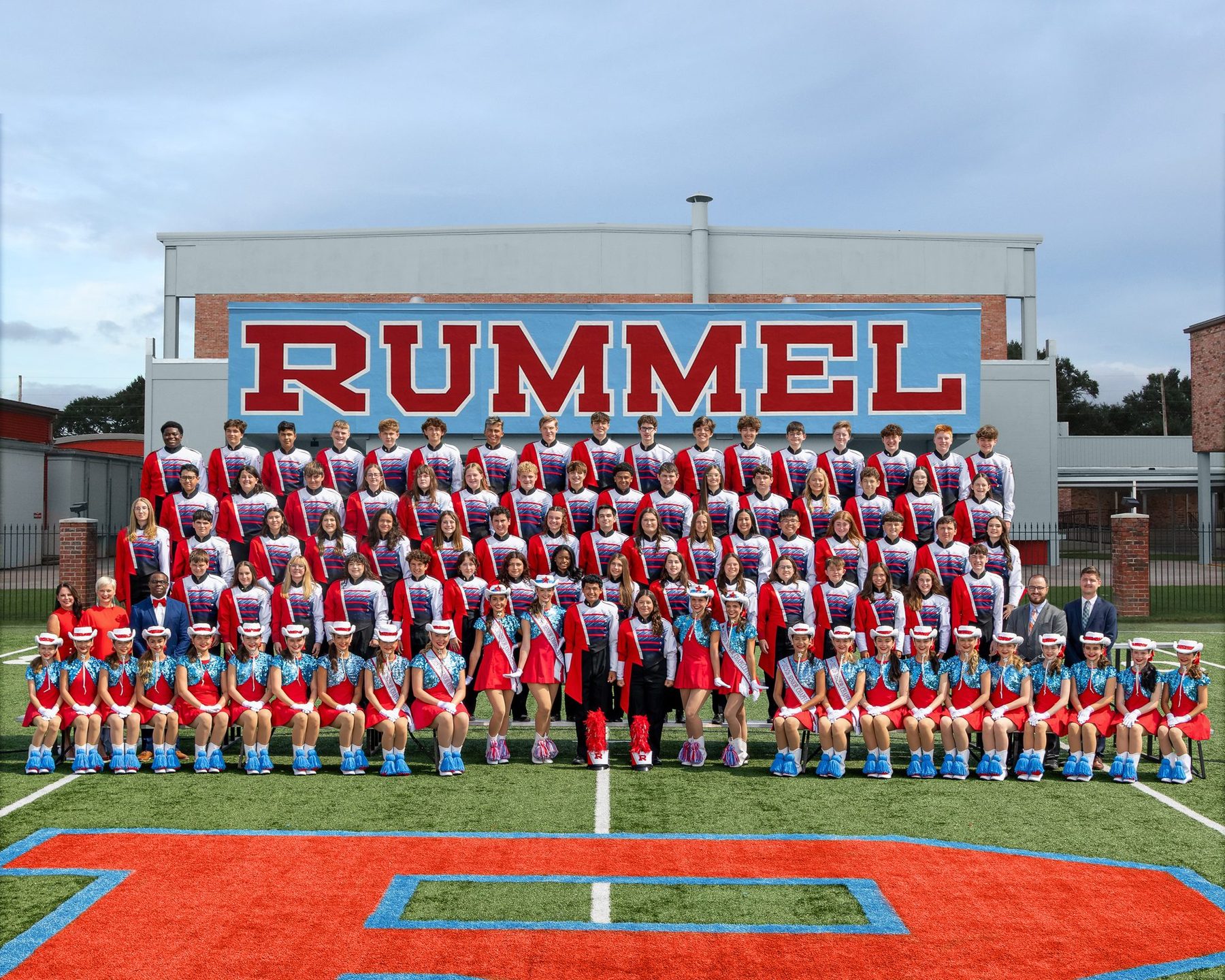 The Raider Band in formation on the field in front of the RUMMEL building