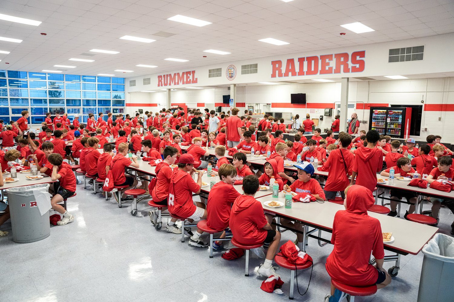 The cafeteria full of students in red shirts under the RUMMEL RAIDERS wall