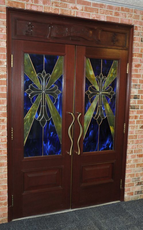 The chapel doors, dark wood with stained glass in blue and gold