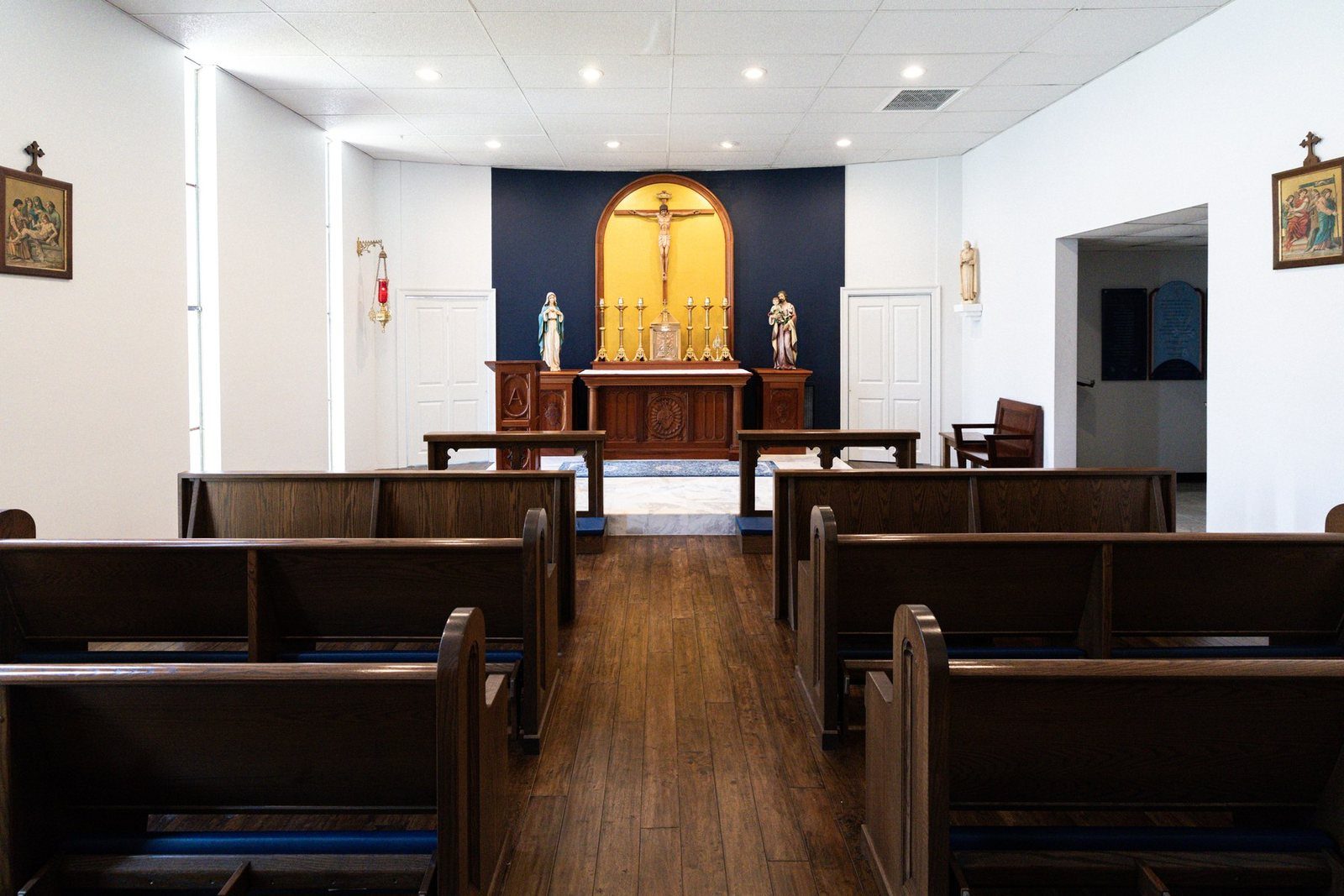 Inside the Chapel of St. Joseph: wooden pews, the altar, and the crucifix on a navy wall