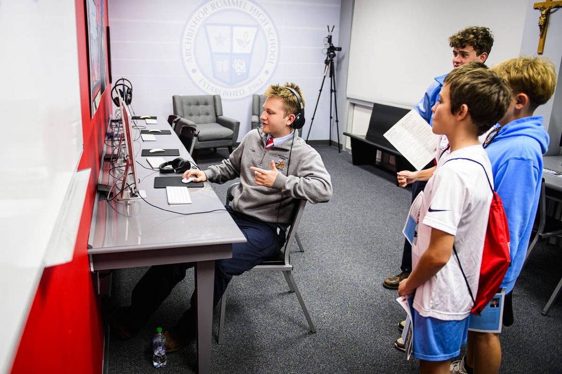 Students at the broadcast desk in the media lab