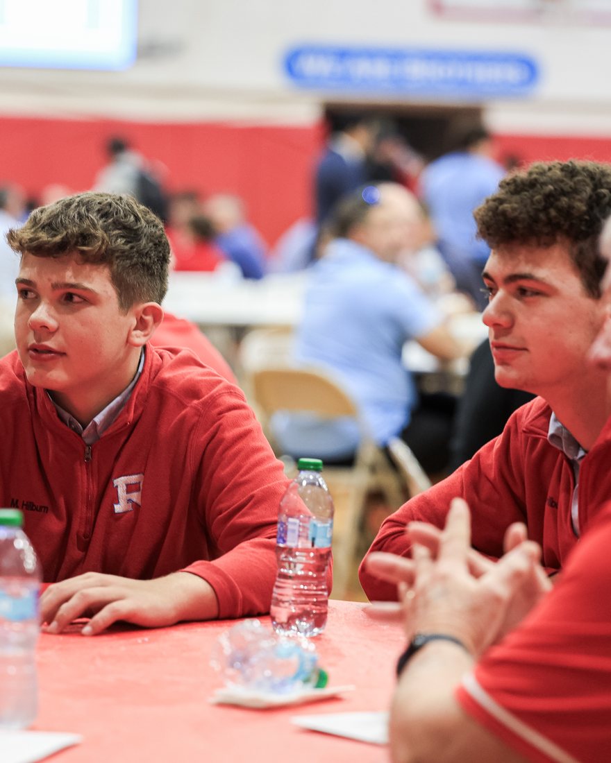 Two Raiders in red talking across a table in the gym