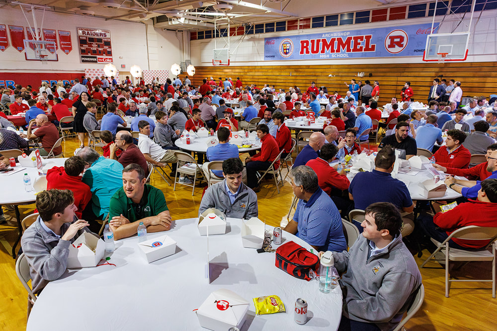 The Rummel gym set with round tables and full of alumni and their sons at lunch
