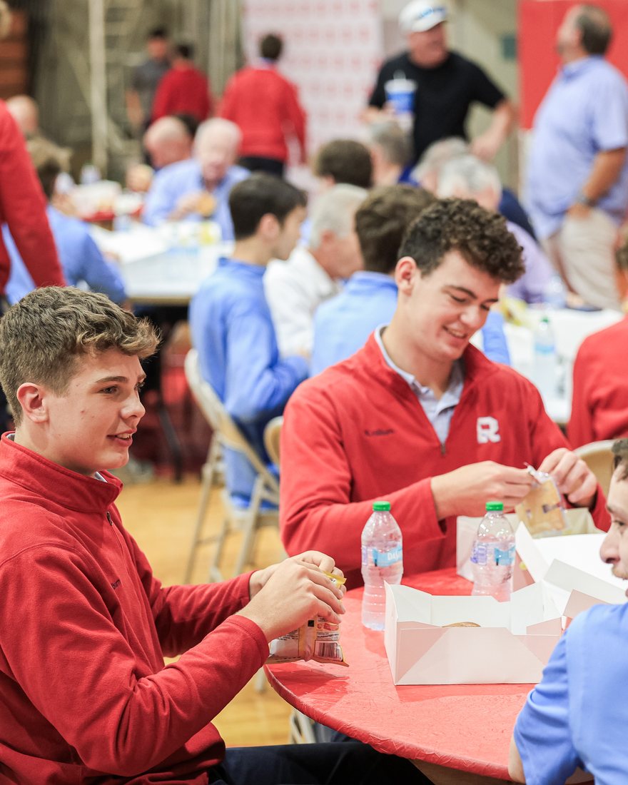 Raiders in red and blue eating lunch together at a round table