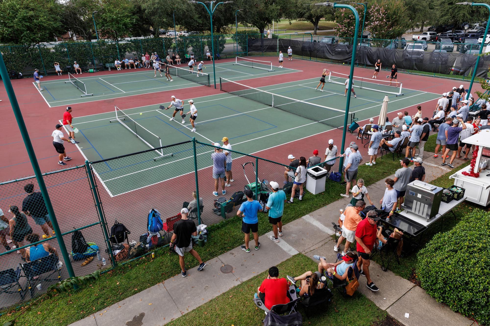 The alumni pickleball tournament under way across the courts at Chateau, with Raiders watching from the sidelines