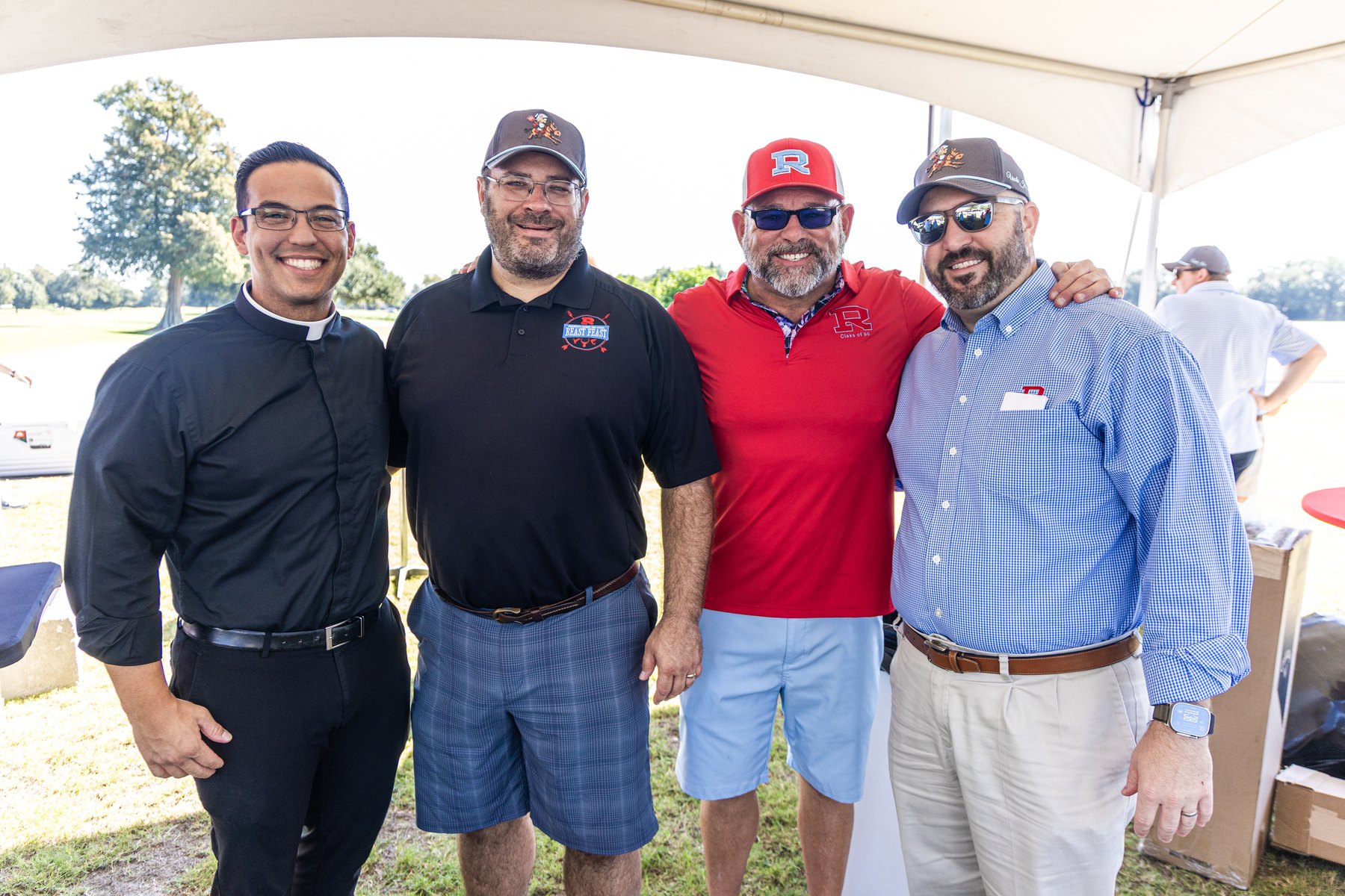 Fr. and three committee members arm in arm under the tent