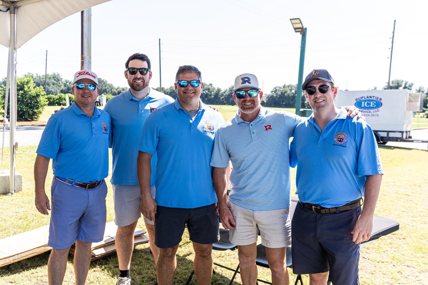 Five Raiders in Columbia blue polos lined up under the tent