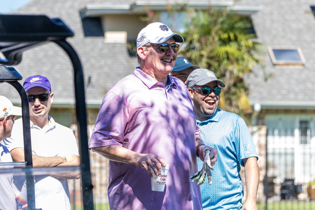 Two alumni laughing beside a golf cart on the course