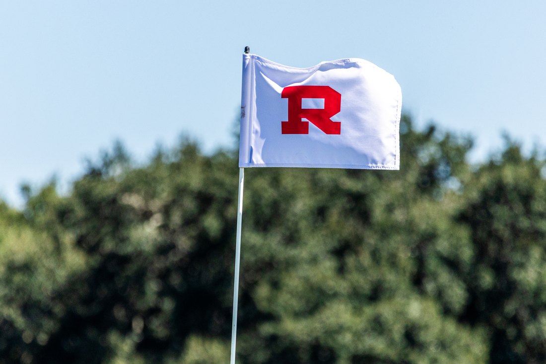 The white R flag on the green against the trees