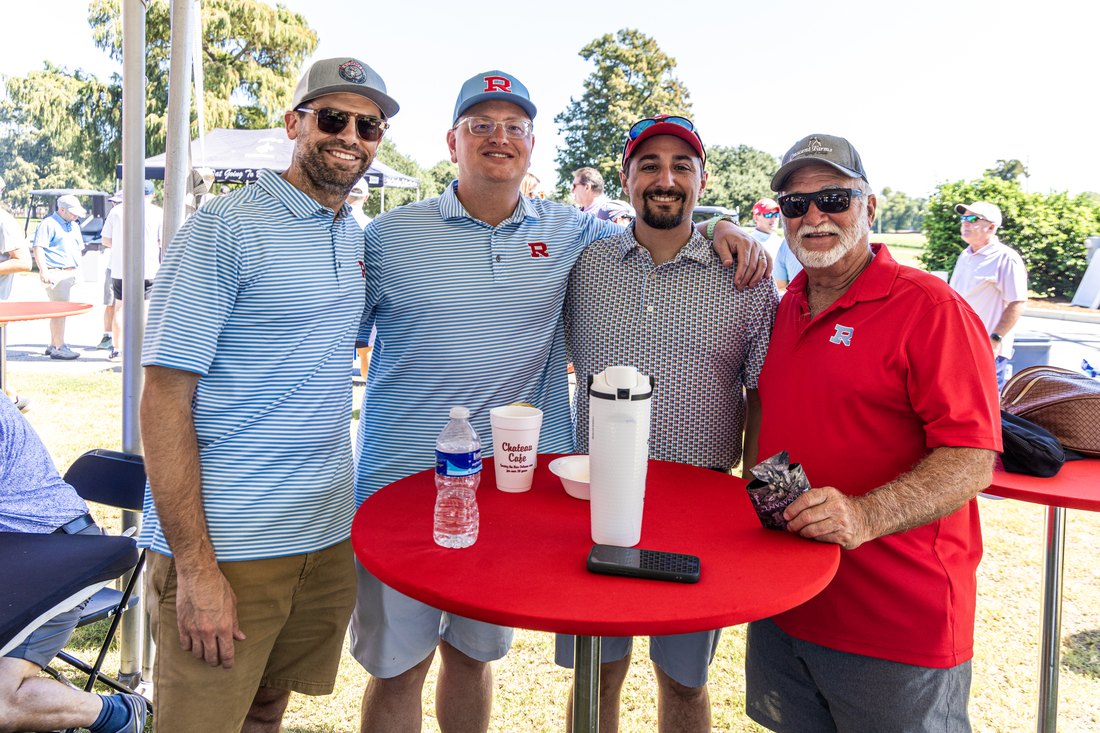 A foursome gathered around a red table under the tent at the 2026 Raider Classic