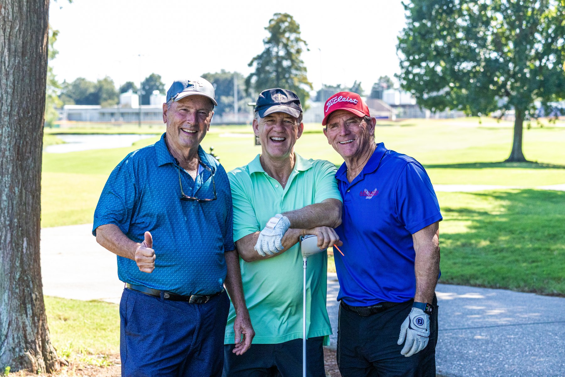 Three Raider golfers arm in arm on the course at the 2026 Raider Classic, one giving a thumbs up