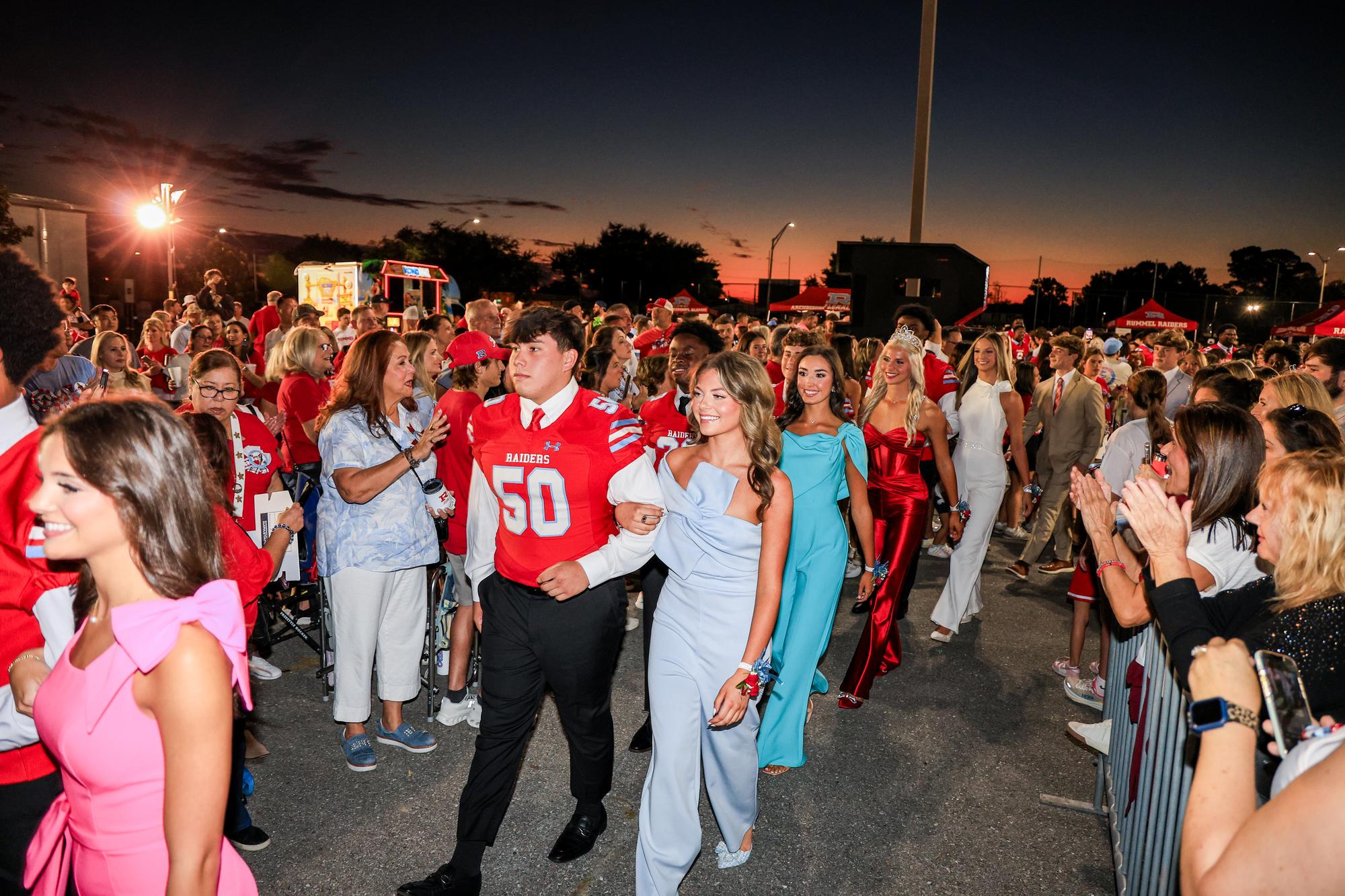 The homecoming court coming through a packed crowd at sunset