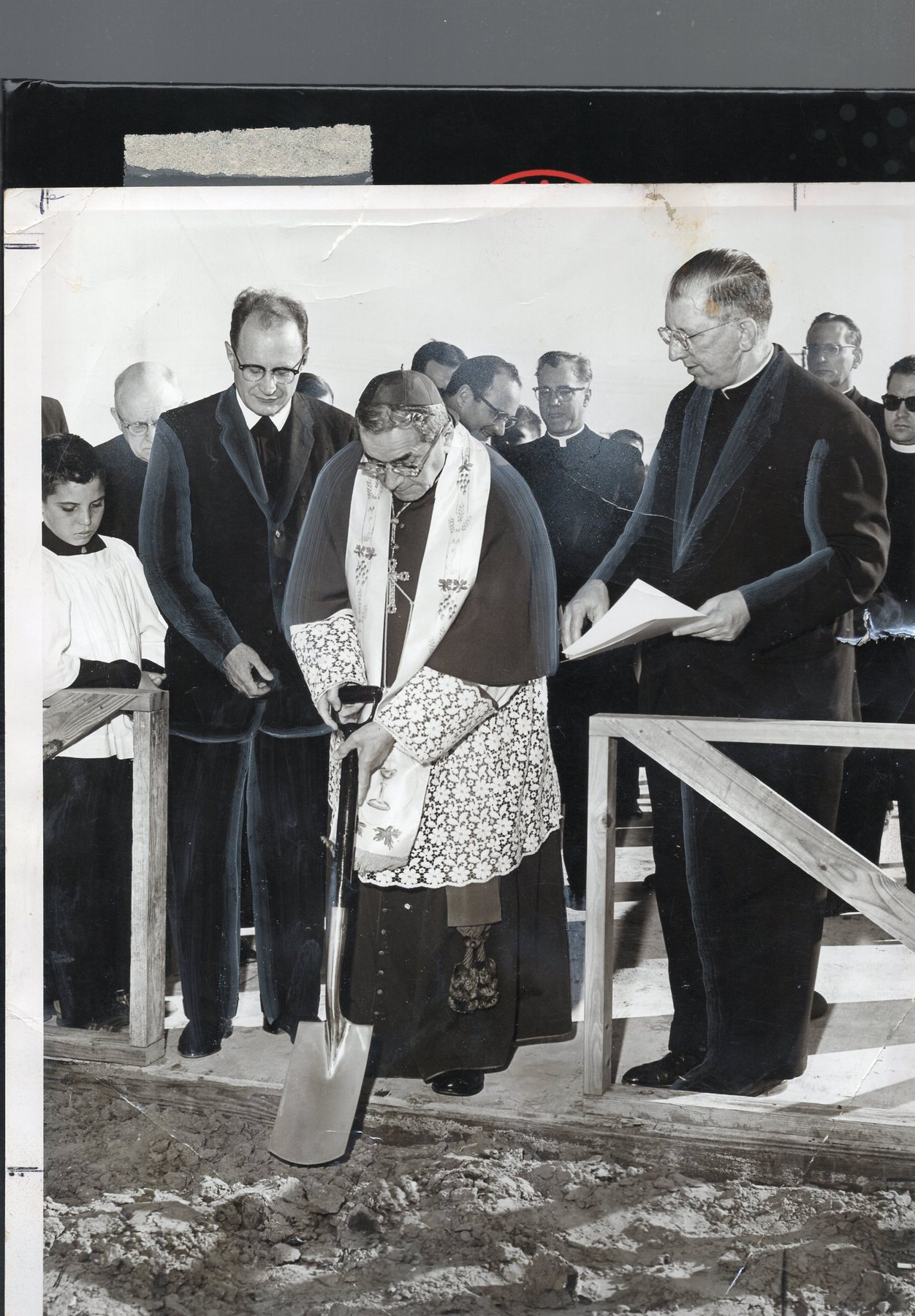 Archbishop Rummel in vestments turning the first spade of dirt at the groundbreaking, September 1961, priests and officials around him