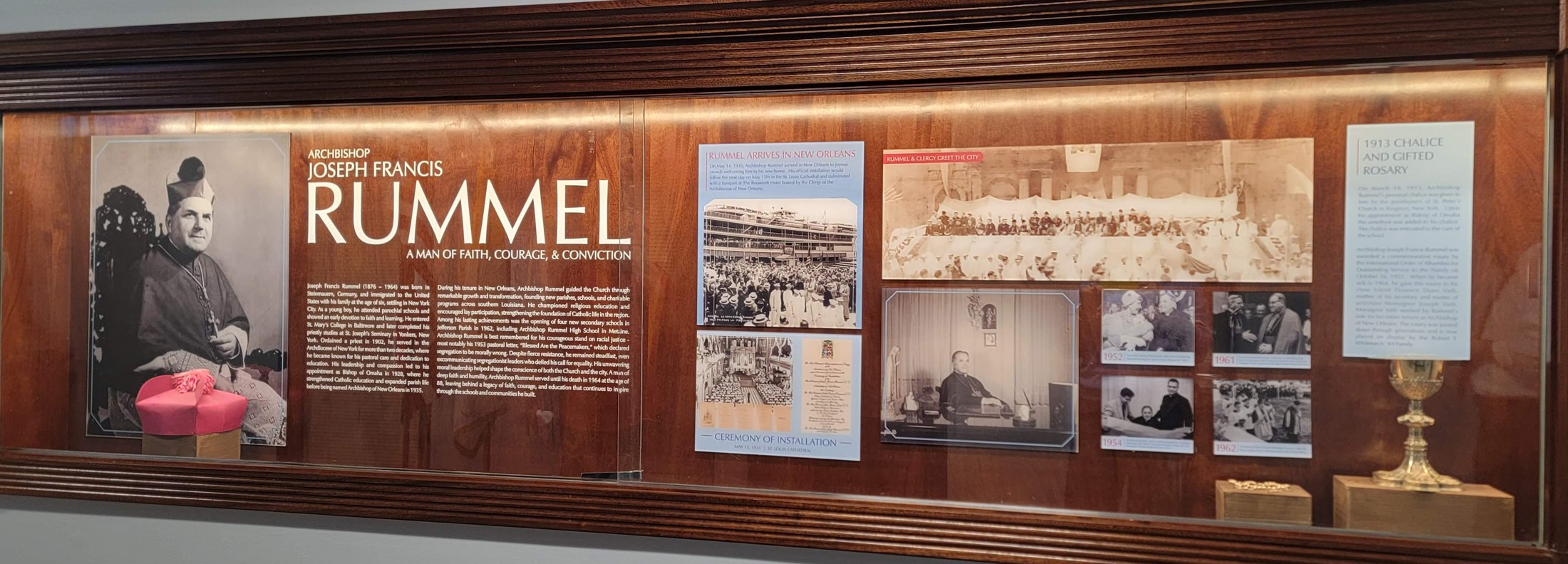 The left end of the display case: the biretta, the 1935 arrival, and the chalice