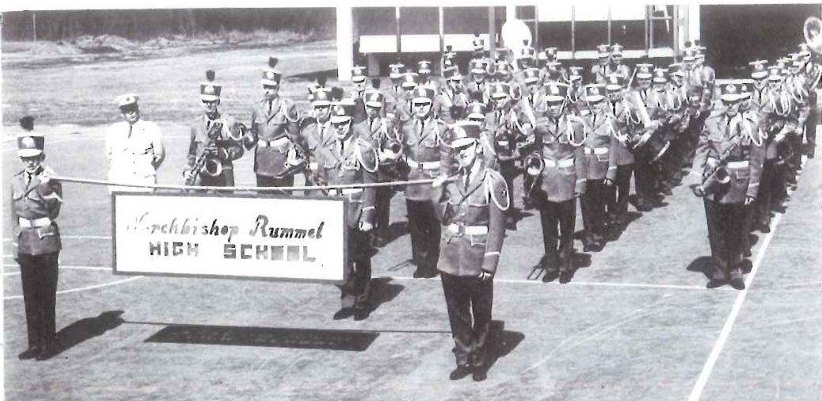 The 1964 marching band behind the Archbishop Rummel High School banner